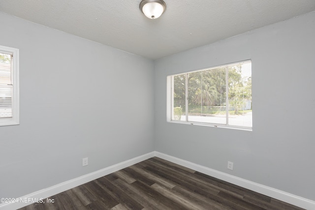 empty room with dark hardwood / wood-style floors and a textured ceiling