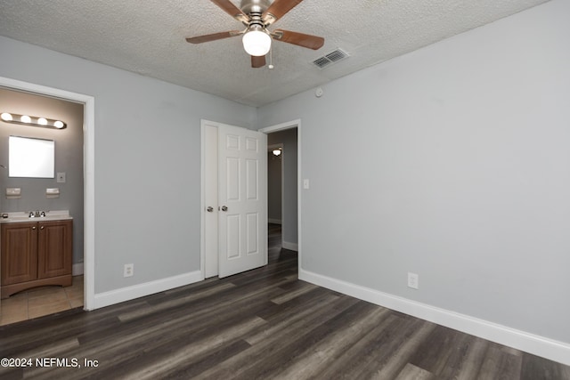 unfurnished bedroom with connected bathroom, sink, dark hardwood / wood-style floors, and a textured ceiling