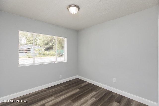 spare room with dark hardwood / wood-style floors and a textured ceiling