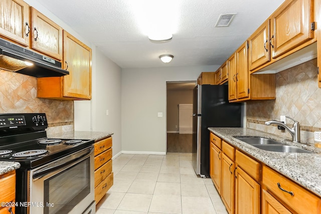 kitchen with light stone countertops, sink, black range with electric cooktop, stainless steel fridge, and light tile patterned floors