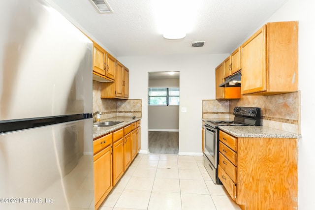 kitchen with stainless steel refrigerator, sink, black electric range oven, backsplash, and light tile patterned floors