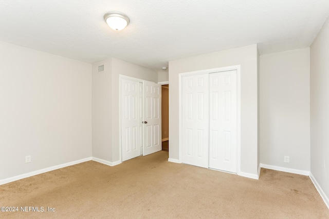 unfurnished bedroom featuring light carpet and a textured ceiling