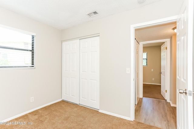 unfurnished bedroom featuring a closet and light colored carpet