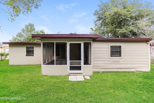 rear view of house featuring a sunroom and a yard