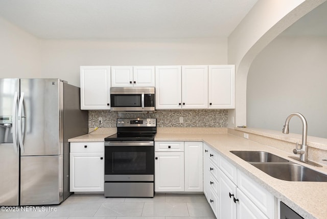 kitchen featuring backsplash, light countertops, white cabinets, stainless steel appliances, and a sink