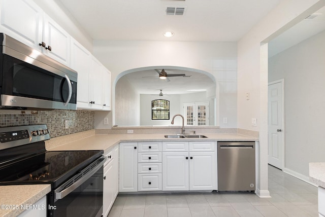 kitchen featuring arched walkways, a sink, ceiling fan, light countertops, and stainless steel appliances