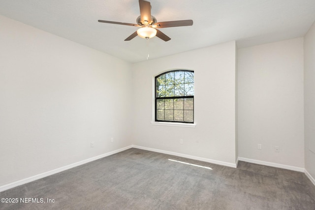 unfurnished room featuring a ceiling fan, dark colored carpet, and baseboards