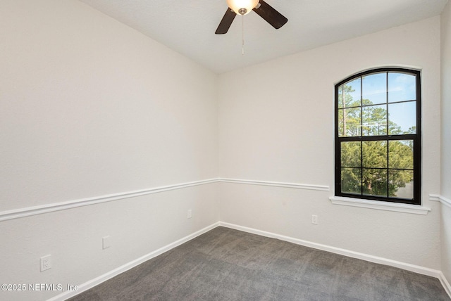 spare room with baseboards, a ceiling fan, and dark carpet