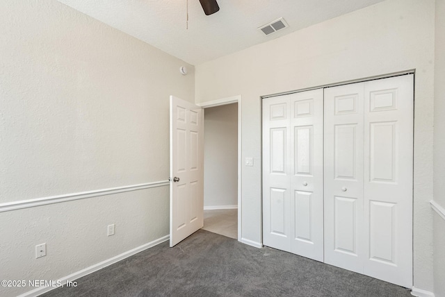 unfurnished bedroom with visible vents, baseboards, dark carpet, a closet, and a ceiling fan