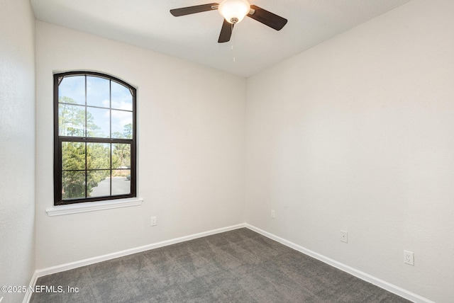 spare room featuring dark carpet, baseboards, and ceiling fan