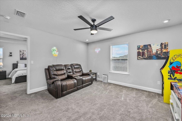 carpeted home theater room with ceiling fan and a textured ceiling