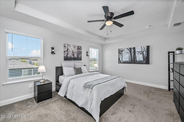 carpeted bedroom featuring ceiling fan, a raised ceiling, and a textured ceiling