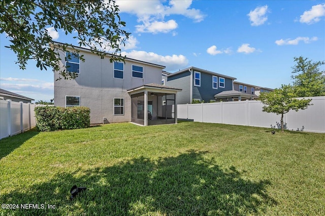 rear view of property with a sunroom and a lawn