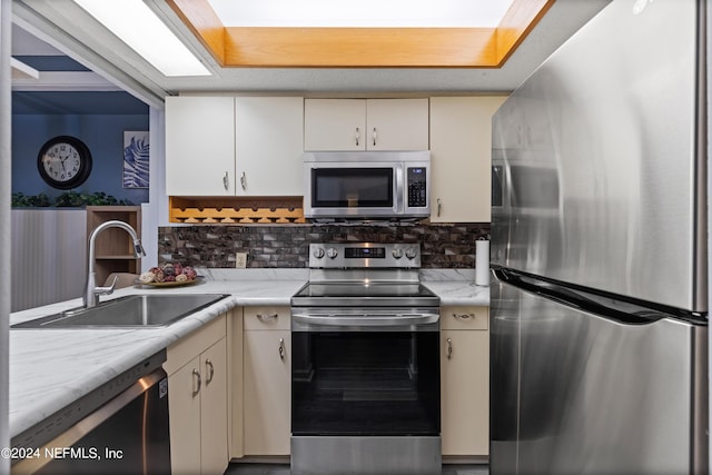 kitchen with light stone counters, sink, appliances with stainless steel finishes, and tasteful backsplash