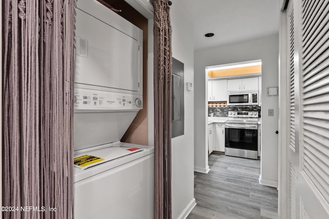 laundry room featuring light hardwood / wood-style flooring and stacked washer / drying machine