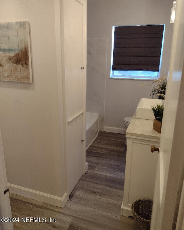 full bath featuring toilet, wood finished floors, vanity, and baseboards