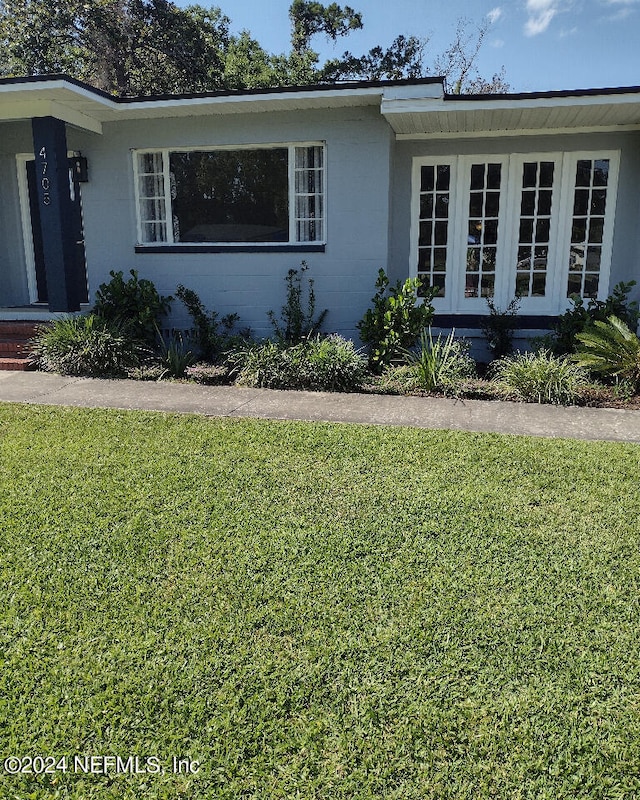 ranch-style home with french doors, a front lawn, and concrete block siding