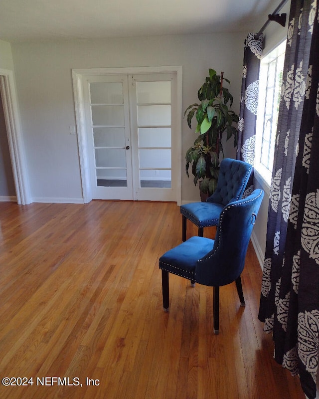 living area with french doors, baseboards, and wood finished floors