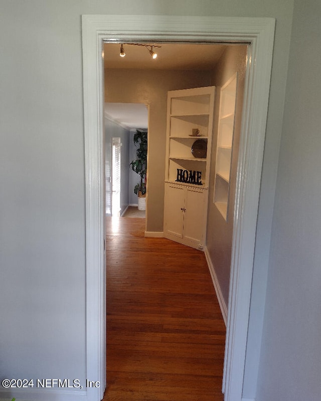 corridor with rail lighting, baseboards, and wood finished floors