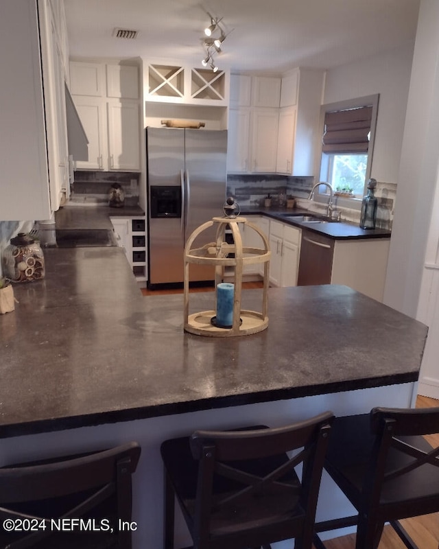 kitchen featuring stainless steel appliances, dark countertops, white cabinets, and a breakfast bar