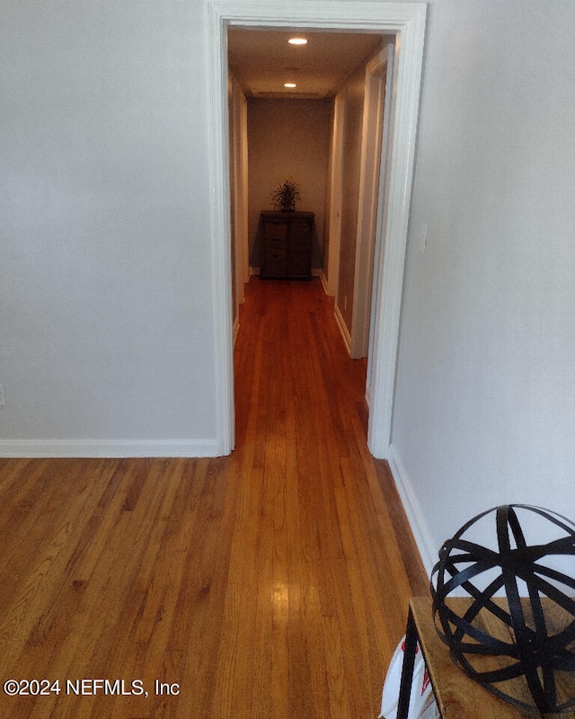 hall with dark wood-style flooring and baseboards