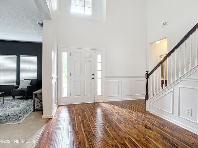 foyer with a high ceiling, a textured ceiling, and dark hardwood / wood-style floors