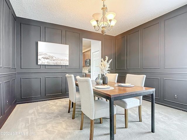 carpeted dining area with a chandelier and a textured ceiling