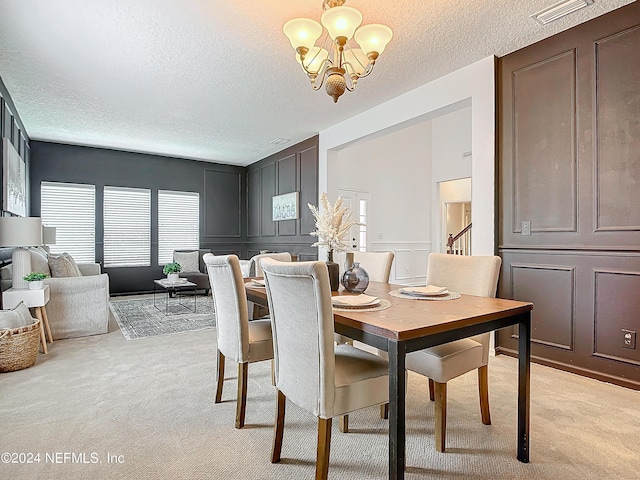 carpeted dining space featuring a chandelier and a textured ceiling