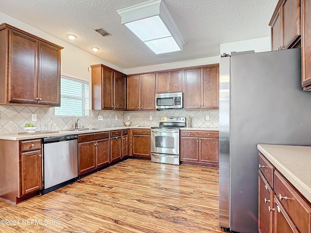 kitchen featuring a textured ceiling, stainless steel appliances, light hardwood / wood-style floors, and sink