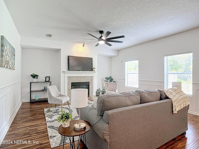 living room with a textured ceiling, dark hardwood / wood-style floors, ceiling fan, and a fireplace