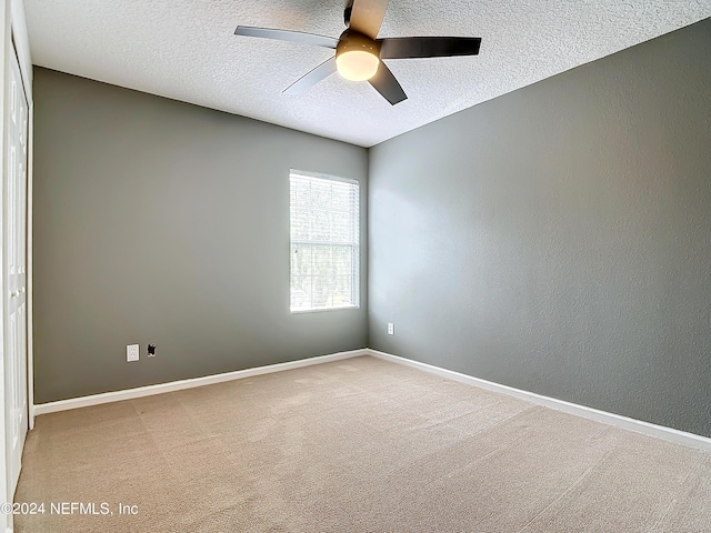 unfurnished room featuring ceiling fan, carpet floors, and a textured ceiling