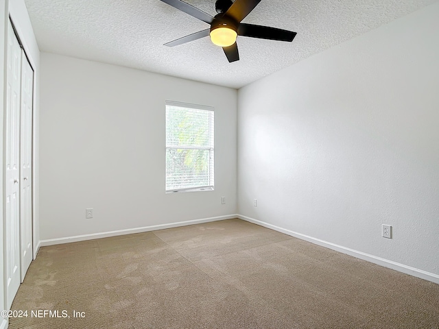 carpeted empty room with a textured ceiling and ceiling fan