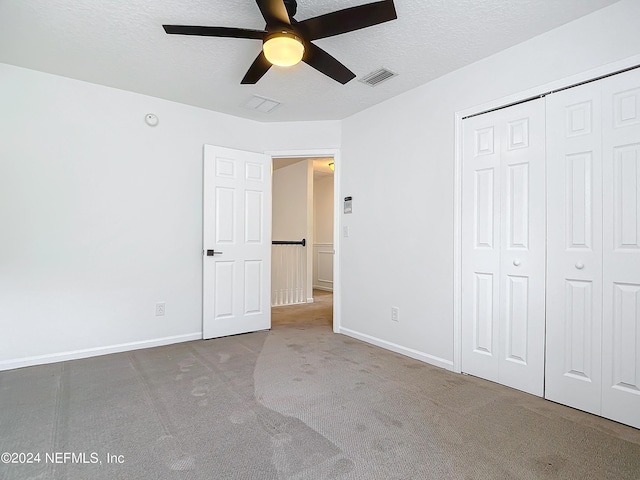 unfurnished bedroom featuring ceiling fan, a closet, carpet, and a textured ceiling