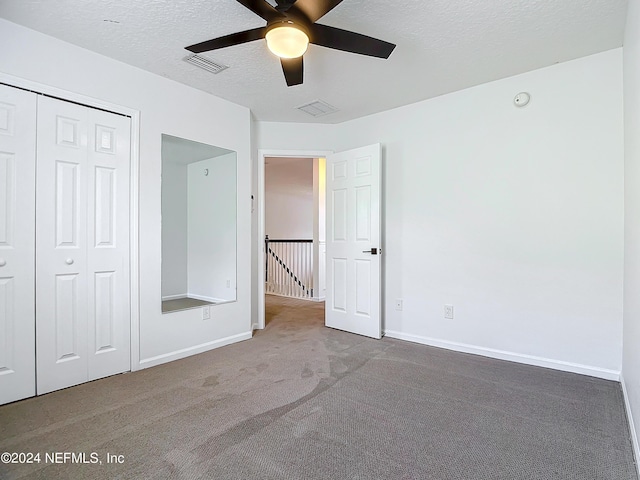 unfurnished bedroom with carpet, a textured ceiling, a closet, and ceiling fan