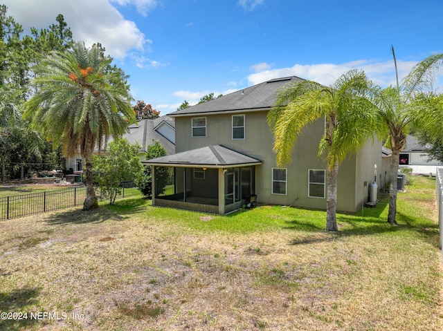 rear view of property with a sunroom, central air condition unit, and a lawn