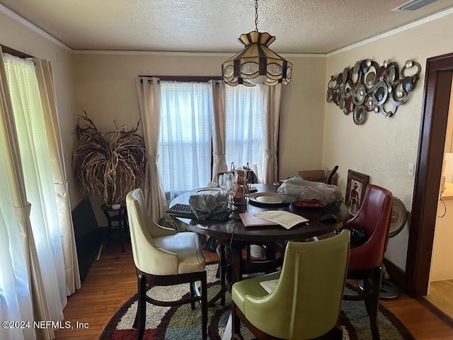 dining room featuring crown molding, a textured ceiling, and wood finished floors