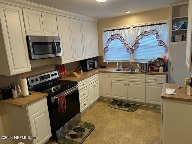 kitchen featuring white cabinets, light floors, stainless steel appliances, and a sink