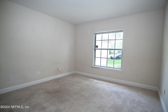 unfurnished room with a textured ceiling, carpet floors, and baseboards