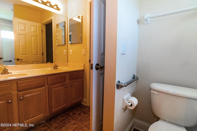 bathroom with double vanity, a sink, toilet, and tile patterned floors