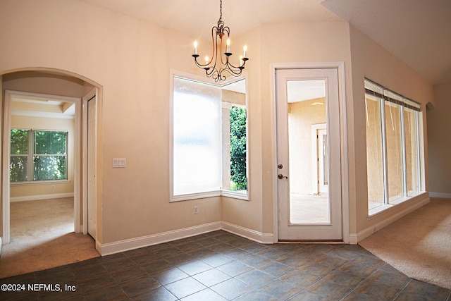 entryway with arched walkways, dark carpet, and baseboards