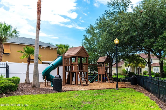 communal playground featuring a yard and fence