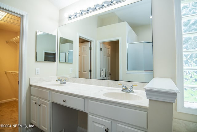 full bathroom with double vanity, a walk in closet, and a sink