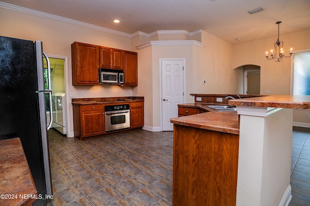 kitchen with a textured ceiling, arched walkways, stainless steel appliances, a sink, and decorative light fixtures