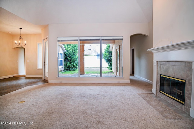 unfurnished living room featuring carpet floors, a fireplace, baseboards, and an inviting chandelier