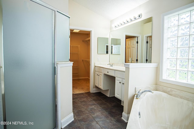 bathroom featuring lofted ceiling, a walk in closet, a textured ceiling, vanity, and a bath