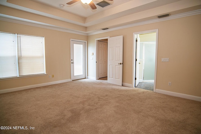 empty room featuring light carpet, ornamental molding, and a raised ceiling