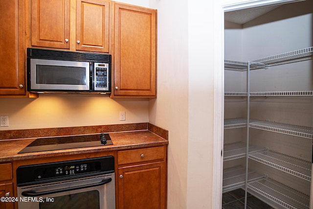 kitchen with appliances with stainless steel finishes, dark countertops, and brown cabinets