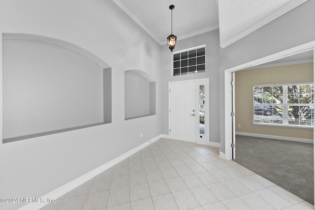 foyer with light tile patterned floors, a textured ceiling, a high ceiling, and ornamental molding