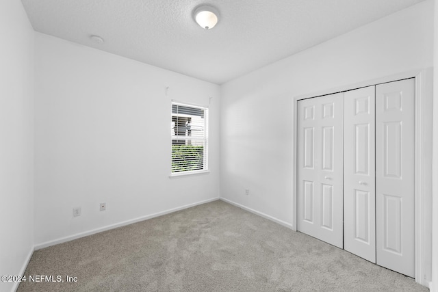 unfurnished bedroom featuring light carpet and a closet