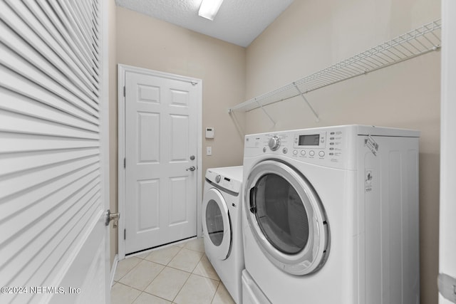 laundry room featuring separate washer and dryer, a textured ceiling, and light tile patterned floors